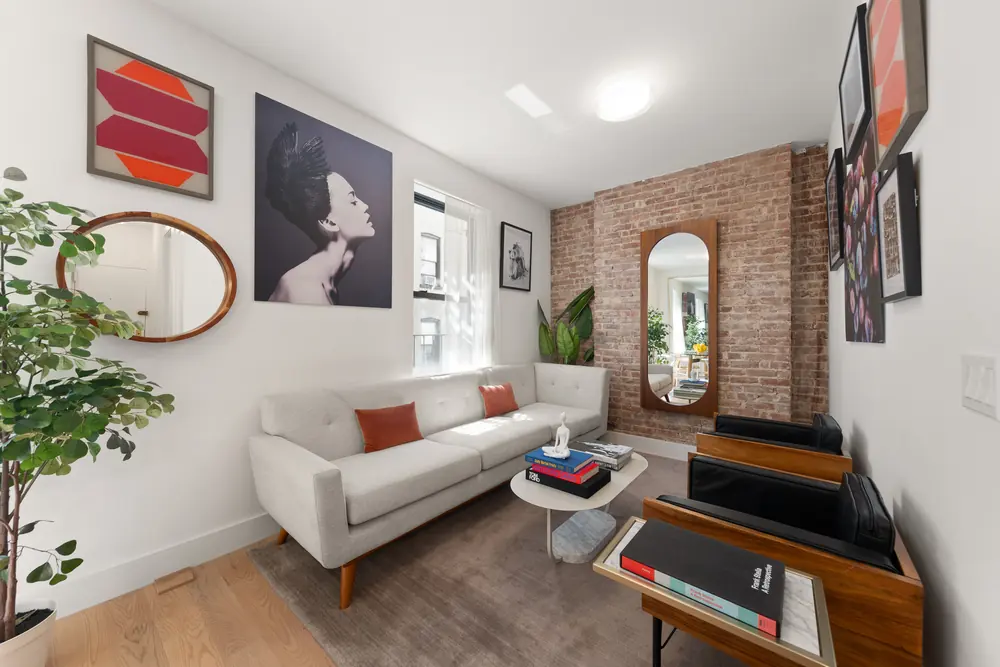 80 Charles Street, Residence 3R: the living room against an exposed brick wall, with an arched mirror and gallery art