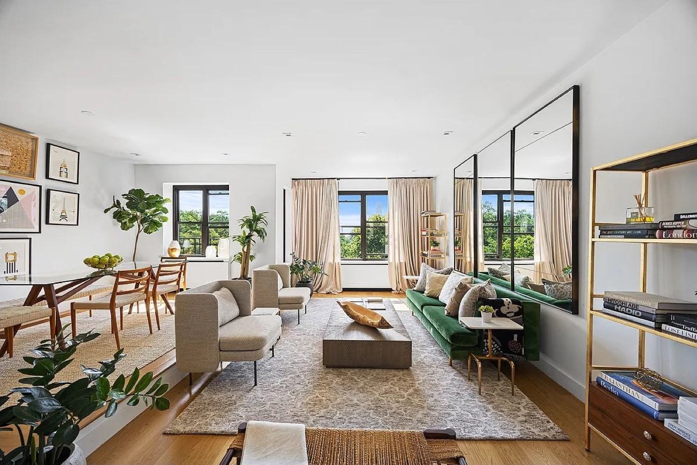 A light-filled living room with a green sofa and park views